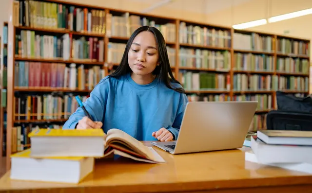 Student studying with a laptop in a library