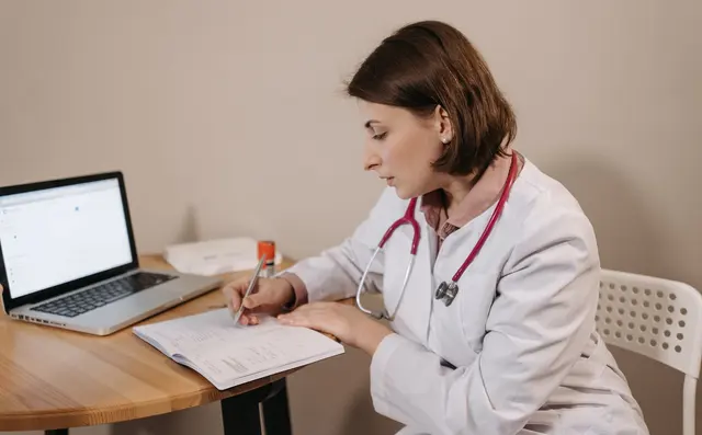 Doctor typing at a computer in a consultation room
