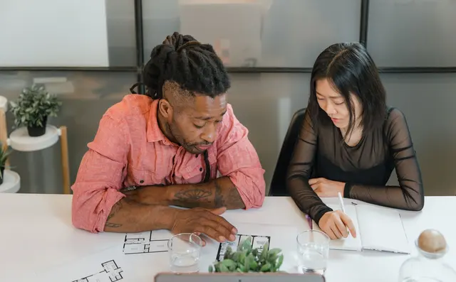 Two people discussing notes across a table