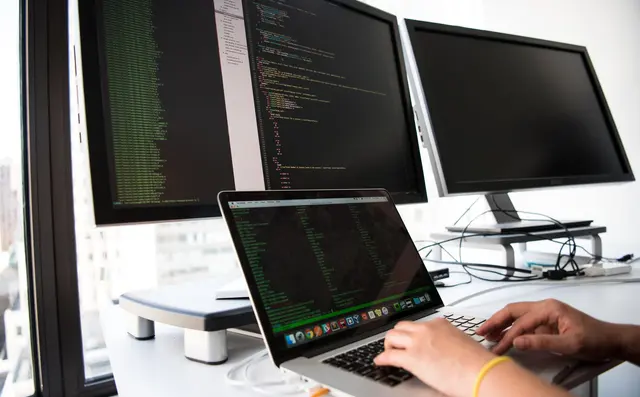 Developer writing code at a two-monitor desk