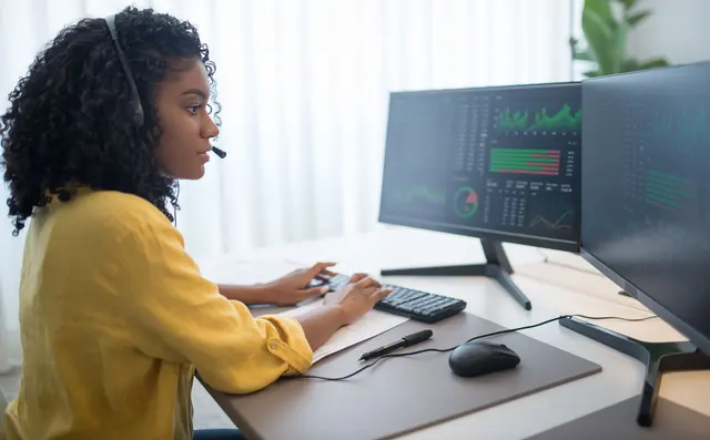 Support engineer with a headset monitoring screens