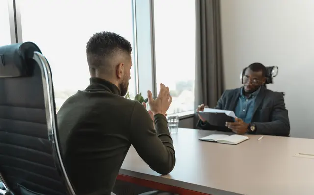 Two people talking across a table in a job interview
