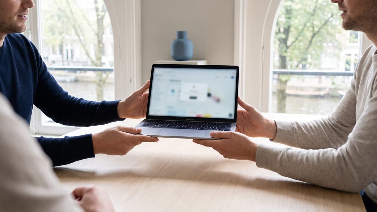 Two people holding a laptop between them with a clickable prototype