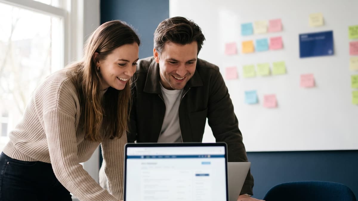 A developer and a product owner reviewing a working web application on a laptop