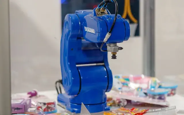 A single blue robot arm at one workstation, doing one job