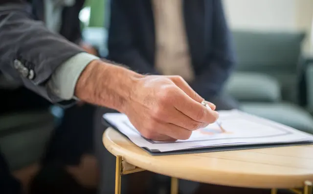 A hand writing on a document at a table