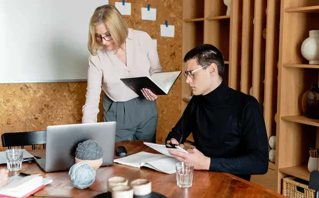 Two colleagues going through notes at a laptop