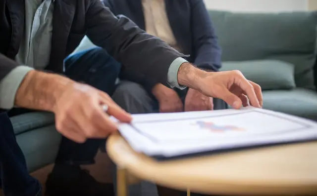 One person handing a printed document to another