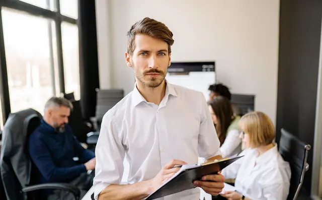 A manager with a clipboard in an office with colleagues
