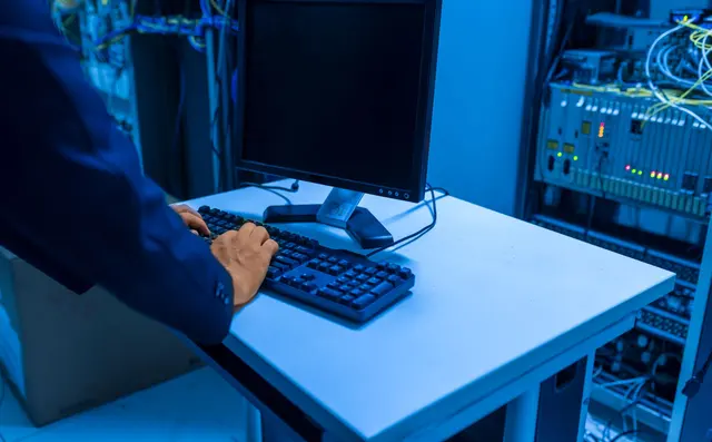 An engineer working at a console in a server room