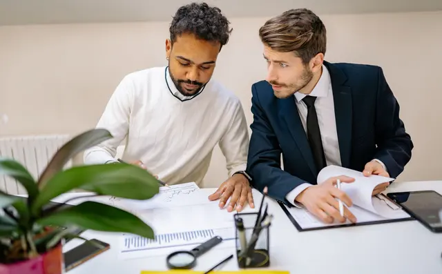 Two colleagues reviewing documents at a desk in an office