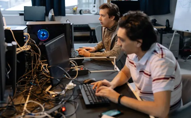 Two engineers working together at their monitors