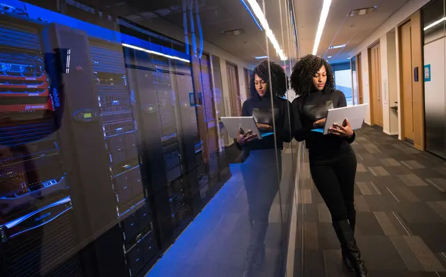 A technician with a laptop between server racks