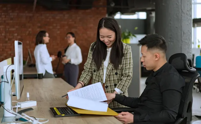 Two colleagues discussing a report at a desk