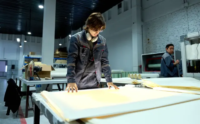 A worker inspecting material on a workbench