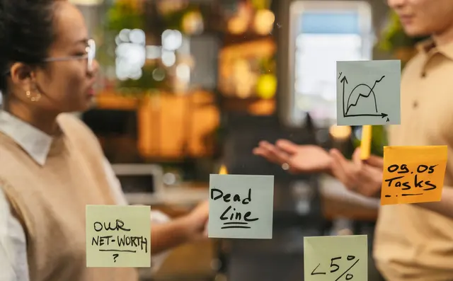 Two colleagues mapping tasks on a glass wall
