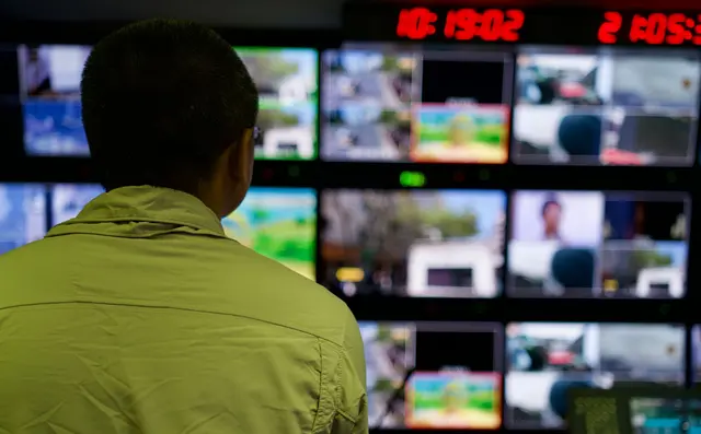 An operator watching a wall of monitoring screens