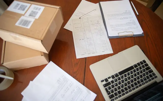 Paper order forms stacked on a desk beside a keyboard