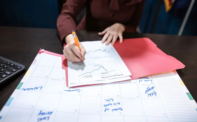 A planner reviewing a schedule on a large printed sheet