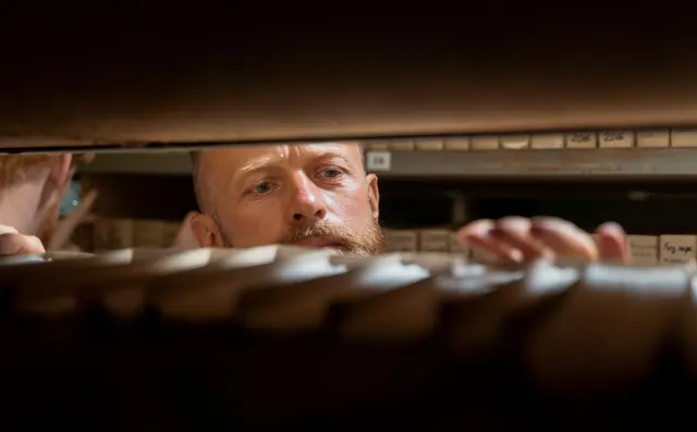 A researcher pulling a specific file from an organised cabinet