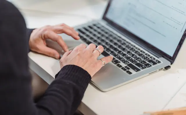 Hands typing on a laptop at a desk