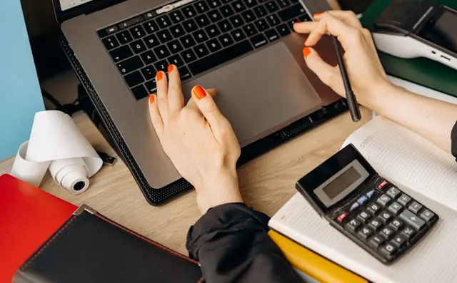 A bookkeeper working with a laptop and a calculator