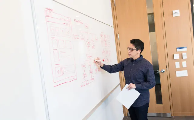 Een engineer schetst een systeemdiagram op een whiteboard