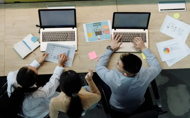 A team reviewing plans with laptops and charts