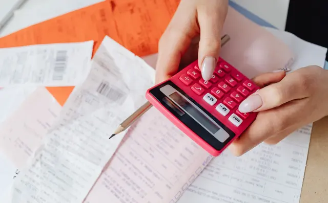 Invoices and consignment notes being checked with a calculator