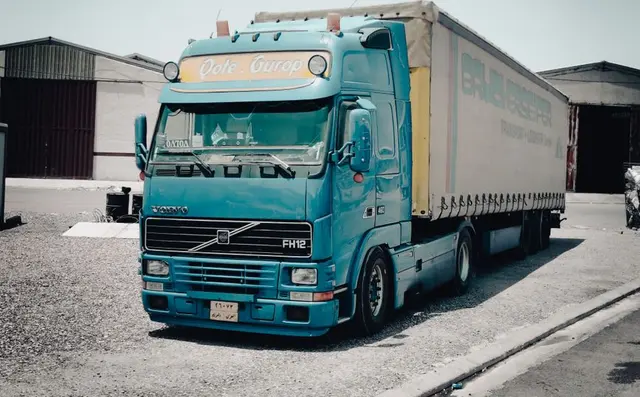A Volvo tractor unit with a curtainside trailer at a depot