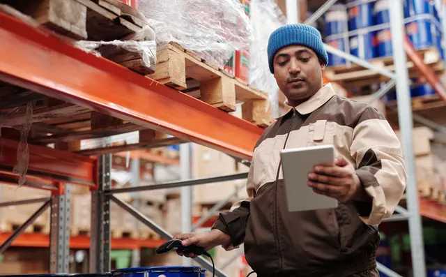 A worker checking stock with a tablet at the racking