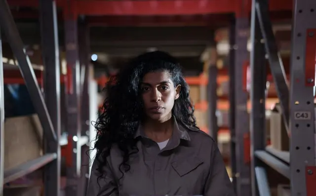 A worker counting stock with a clipboard among the racking